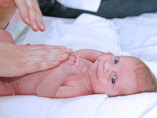 Ein Baby liegt auf dem Rücken und wir massiert